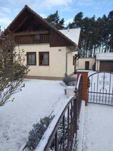 a house with a snow covered yard with a fence at Ferienhaus Villa Waldblick in Kolkwitz +36 photos