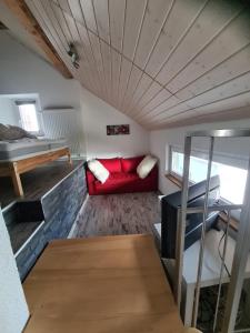 a living room with a red couch and a bed at Joly Gîte in Les Bois