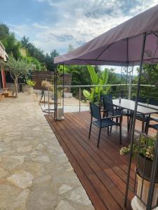 a wooden deck with a table and chairs and an umbrella at Chambre d hote in Le Tignet