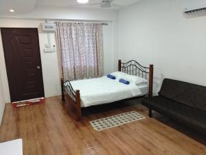a small bedroom with a bed and a couch at HG Homestay in Kota Kinabalu