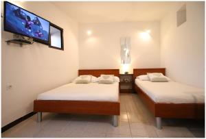 two beds in a room with a tv on the wall at Apartment Karmela in Primošten
