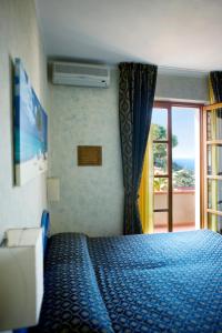 a bedroom with a blue bed with a window at Hotel Corallo in Pomonte