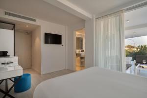a white bedroom with a large bed and a television at Hotel Napa Suites (Adults Only) in Ayia Napa