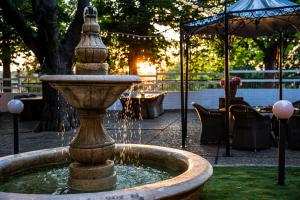 a fountain in a park with a table and an umbrella at Grand Hotel Riga in Ruse
