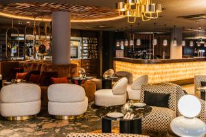 a lobby with chairs and tables and a bar at NYX Hotel Amsterdam Rembrandt Square in Amsterdam