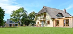 a house with a thatched roof on a grass field at Ferienwohnungen Boddenfischer in Born