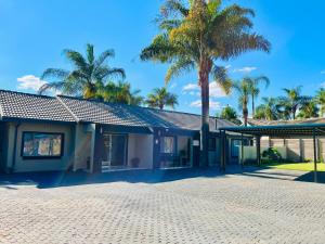 a building with palm trees in front of it at No 80 At Erasmus in Polokwane