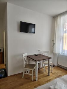 a dining room table with two chairs and a television on the wall at Sankt Johannerhof in Ternitz