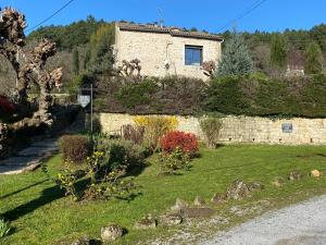 a stone house on a hill with a garden at Mas de lasquiers in Saint-Paul-le-Jeune
