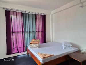 a bed in a room with a window with purple curtains at Changey Inn-Kolakham in Rishop