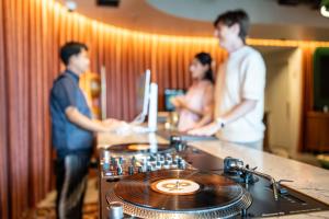 a group of three people standing around a dj table at &Here SHINJUKU in Tokyo