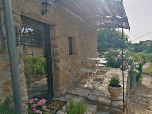 a stone building with a patio with a table and chairs at Mas de lasquiers in Saint-Paul-le-Jeune