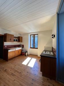 a large kitchen with wooden floors and a large window at La compagnie du bourg in Le Châtelard