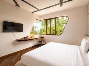 a bedroom with a bed and a desk with a television at Modern 1-BR Loft with Art Deco Style Shared Pool in Canggu +19 photos