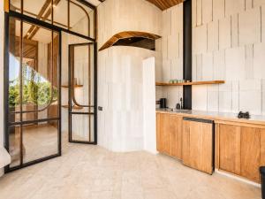 an open kitchen with wooden cabinets and a glass door at Modern 1-BR Loft with Art Deco Style Shared Pool in Canggu