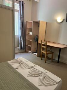 a room with a bed and a desk and a table at Le Terminus in Tarascon