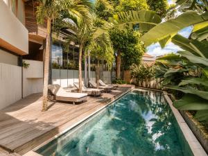 a swimming pool with chairs and palm trees next to a house at Modern 1-BR Loft with Art Deco Style Shared Pool in Canggu