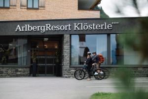 two people on a bike in front of a store at ArlbergResort Klösterle in Klösterle