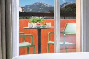 a table and chairs on a balcony with a view of a mountain at Kyriad Chambéry Centre - Hôtel et Résidence in Chambéry