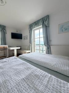a bedroom with two beds and a desk and a window at Pension Semler in Mondsee