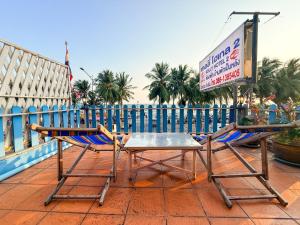 a table and chairs on a patio with a sign at Kelly Hotel Bangsean in Ban Laem Thaen
