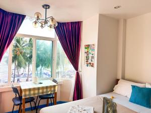 a bedroom with a bed and a desk and a window at Kelly Hotel Bangsean in Ban Laem Thaen