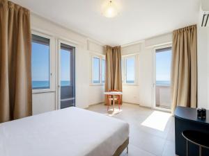 a bedroom with a bed and a desk and windows at B&B HOTEL Pesaro Des Bains in Pesaro