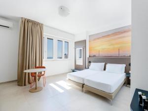 a bedroom with a bed and a desk and a table at B&B HOTEL Pesaro Des Bains in Pesaro