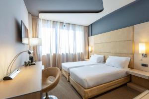 a hotel room with a bed and a desk and a bed sidx sidx sidx sidx at B&B HOTEL Expo Verona Villafranca in Villafranca di Verona