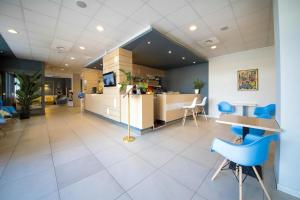 an office lobby with blue chairs and a counter at B&B HOTEL Mantova Cristallo in Virgilio +20 photos