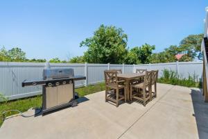 a patio with a table and a grill and chairs at Luxury 4BR, Across street from beach, Sleeps 10! in Gulf Shores +41 photos