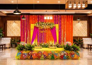 eine Bühne mit rosa und orangefarbenen Vorhängen und Blumen in der Unterkunft Hotel Woodlark Square Zirakpur Chandigarh # Family Hotel # Property of the Year in Chandīgarh