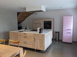 a kitchen with a pink refrigerator and a table at Maison de vacances tout Confort au Calme avec Jardin clos in Saint-Just-près-Brioude