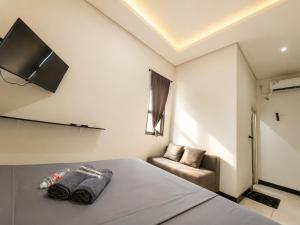 a bedroom with a bed and a couch and a flat screen tv at NamRoom at Kalimalang in Cibening