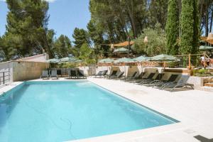 a swimming pool with chairs and umbrellas at Domaine de l'Oustalia in Aix-en-Provence