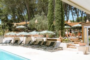 a group of chairs and umbrellas next to a pool at Domaine de l'Oustalia in Aix-en-Provence