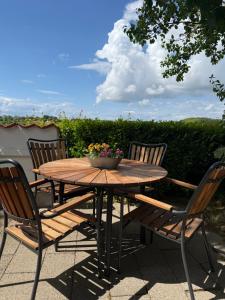 a wooden table with four chairs and a bowl of flowers at Digebjerggaard Bed & Breakfast in Vester-Skerninge