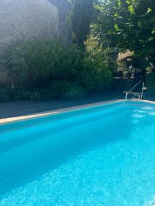 a swimming pool with blue water in a yard at Maison d'Hôtes Les Sources in Villedieu