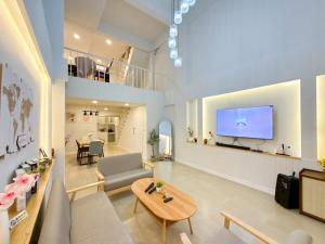 a living room with a couch and a tv on a wall at Kelly Hotel Bangsean in Ban Laem Thaen