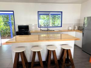 a kitchen with a counter with four stools around it at Kuki Kainga in Matavera
