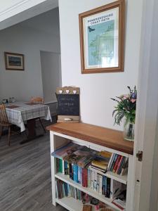 a book shelf full of books with a table at Harbourlight Guesthouse in Saundersfoot