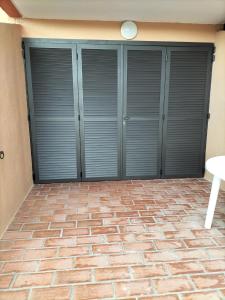 a garage with gray doors and a brick floor at Le Cocon de Laeti & Steph in Port Leucate