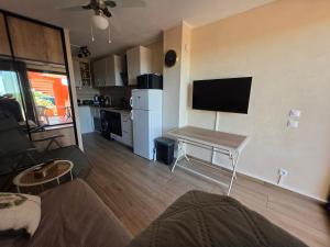 a living room with a couch and a table with a television at Le Cocon de Laeti & Steph in Port Leucate