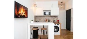 a kitchen with a counter with stools and a fireplace at Doux Pavillon - La Palmeraie in Nice