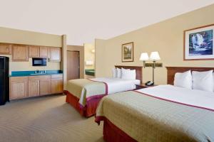 a hotel room with two beds and a kitchen at Pinedale Hotel & Suites in Pinedale