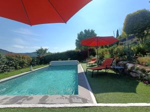 a pool with a red umbrella and a table and a chair at Le jardin de Nigelle , En Provence in Mallemoisson