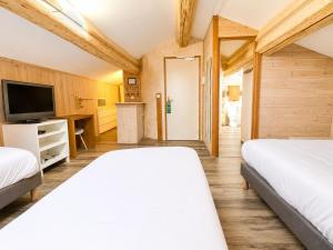 a bedroom with two beds and a flat screen tv at Le Relais de la Calèche in Le Beausset