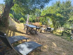 ein Picknicktisch und Stühle in einem Park mit einer Schaukel in der Unterkunft Saisonnée - Chambres d'Hôtes et Table d'Hôtes en Aveyron in Centrès