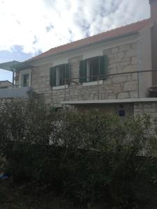 una casa de piedra con persianas verdes. en Apartman Ante, en Murter