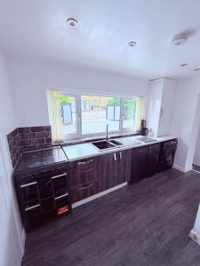 a kitchen with black cabinets and a sink and a window at Anex Highfield Guest House in Idle